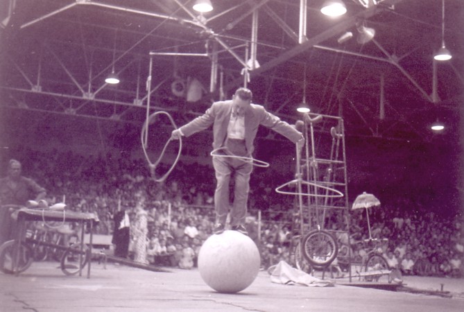 Circus performer balancing on a ball with hoops